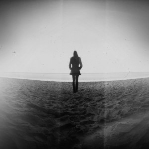 A black-and-white silhouette of a girl standing in a deserted wasteland