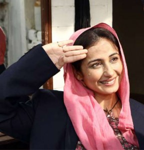 A still of actor Divya Dutta from the film 'Bhaag Milkha Bhaag'. She is wearing a pink headscarf and bloue jacket, and her right palm is held up to her head in the manner of a salute.