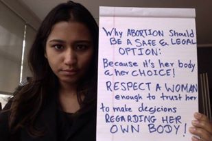 A woman from Sri Lanka holding up a placard which has information on why abortion should be legal