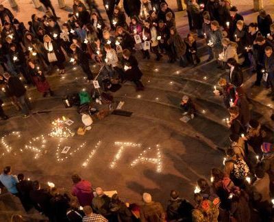Photo of a candlelight vigil, showing a gathering of people coming together to write the name 'Savita' using candles