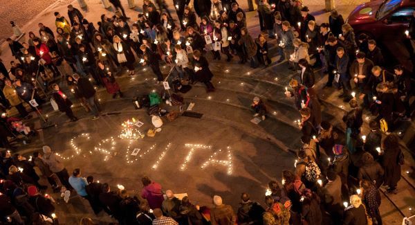 Photo of a candlelight vigil, showing a gathering of people coming together to write the name 'Savita' using candles