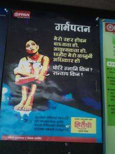 A poster for abortion rights in Nepal, showing a woman sitting with her legs pulled close to her chest. There is abortion-related information written beside her in hindi.