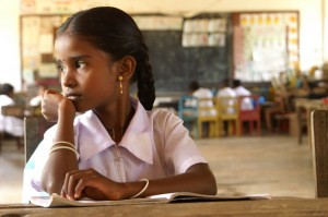 A picture of a girl child. She is wearing a pink frock and is staring to her left.