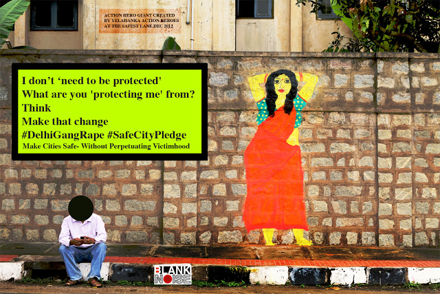 photo shows a brown wall which has an illustration of a woman dressed in a red saree and blur blouse. a man sits in fron of the wall, but his face is blacked out. The message written on the wall says, "i don't 'need to be protected'/ What are you 'protecting me' from? / Think / Make That Change #DelhiGangRape #SafeCityPledge