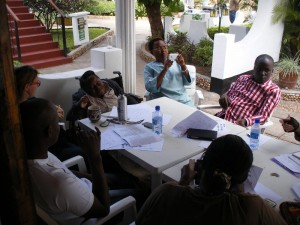 A group of African activists are seated around a table, seemingly engaged in a discussion