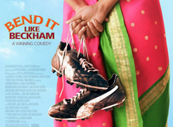 Poster for the film 'Bend It Like Beckham' showing a girl standing with her back facing the camera. She's wearing a cvolourful magenta and green sari and is holding sports shoes in her hands.