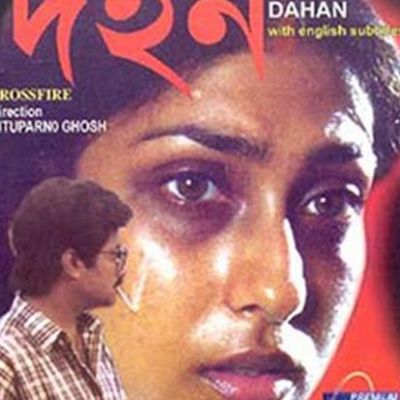 Poster for the Bengali film, 'Dahan', showing a woman's face enlarged and facing the camera, and the smaller figure of a man dressed in a chequered shirt looking at her