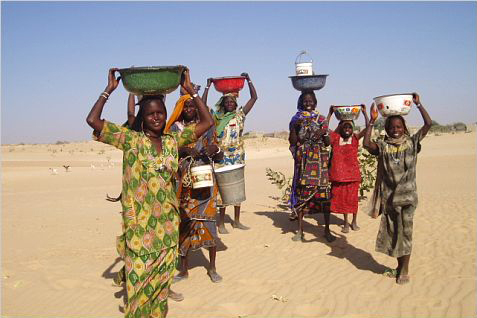 a picture of female migrant workers carrying vessels on their head