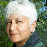 Headshot of Tejaswini Niranjana. She has white hair, and is wearing a green dupatta around her neck. She is smiling at the camera.