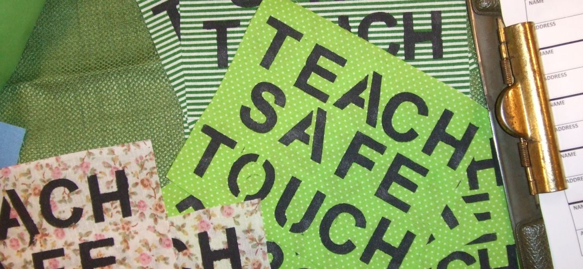 A series of pink and green placards that read 'Teach Safe Touch'