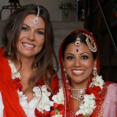 Photo of a lesbian couple, one of them dressed in Indian bridal clothes and the other dressed in Western bridal clothes