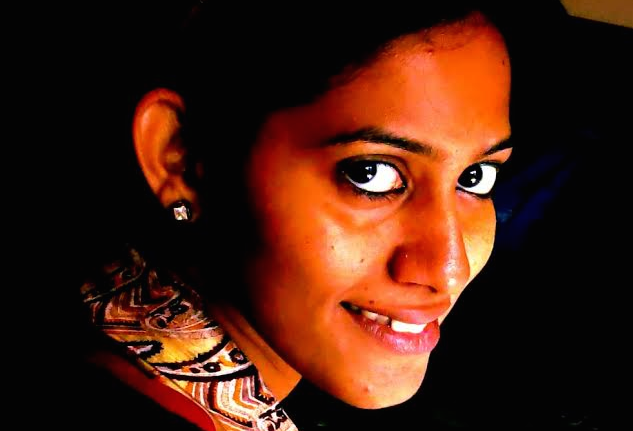 Headshot of a smiling woman with hair tied back and wearing a pearl earring