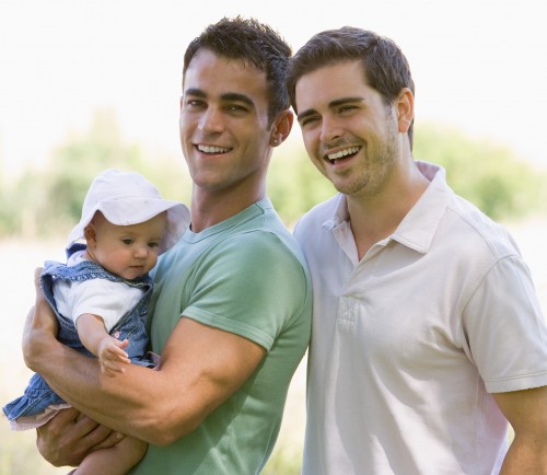 Photo of a gay couple holding a toddler in their arms