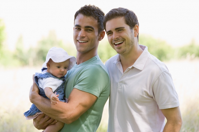 Photo of a gay couple holding a toddler in their arms
