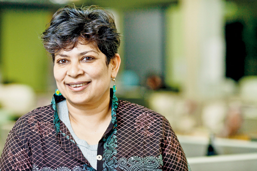 Bishakha Datta with short hair, wearing green earrings, and a brown top.