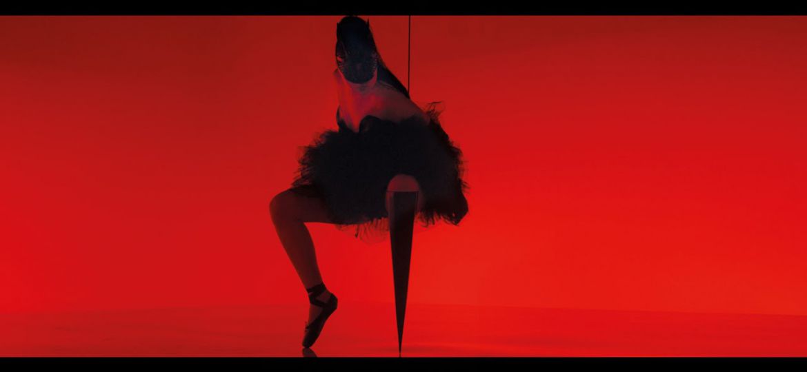 Against a red backdrop, the silhoutte of a dancing woman wearing a flare skirt