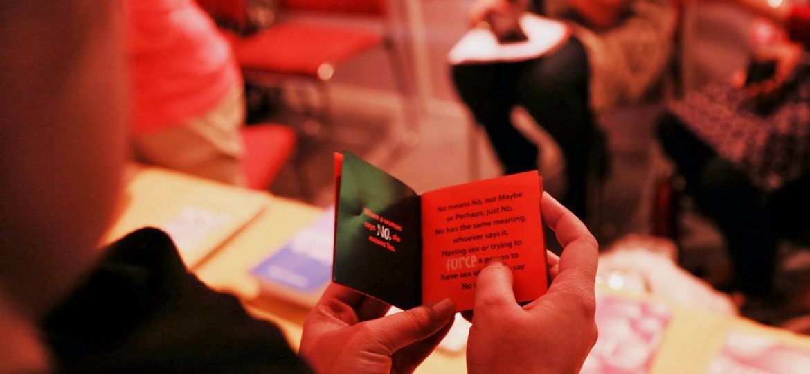 A woman reading a very small and thin book.