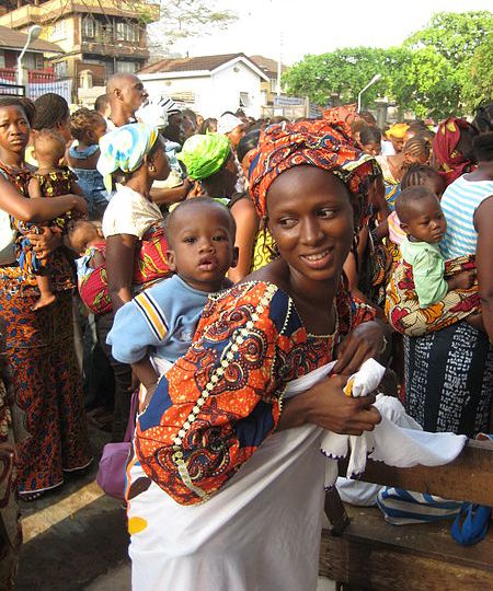 Photo of several African women wearing colourful clothing carrying babies on their backs.