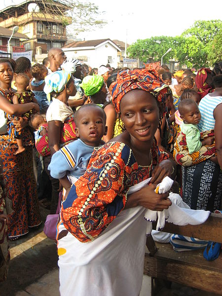 Photo of several African women wearing colourful clothing carrying babies on their backs.