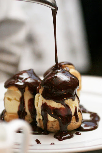 Chocolate sauce being poured on a three-layered butterscotch icecream.