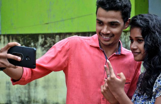 A young boy and girl taking a selfie, doing the victory gesture with one hand. The boy wears a pink shirt, and the girl wears a blue top. Screen reader support enabled. A young boy and girl taking a selfie, doing the victory gesture with one hand. The boy wears a pink shirt, and the girl wears a blue top.