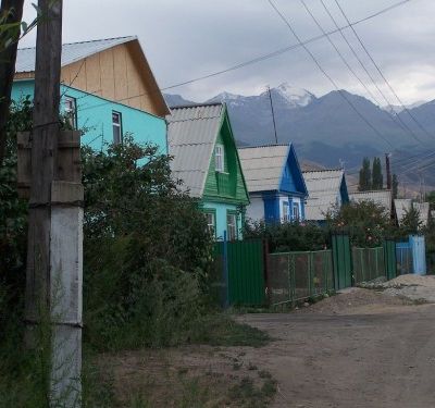 Street with tin roof houses in a hilly area. Snow-capped mountains can be seen behind.