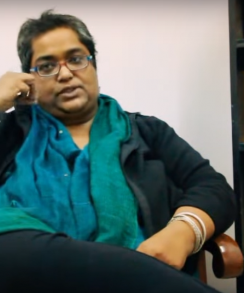 Picture of feminist activist Pramada Menon. She has short hair and glasses, and is wearing a black kurta and green dupatta