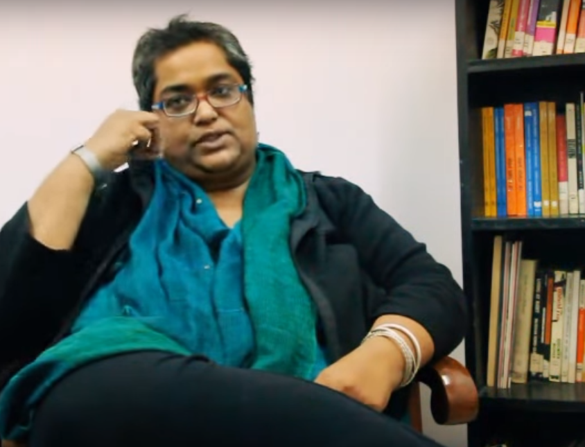 Picture of feminist activist Pramada Menon. She has short hair and glasses, and is wearing a black kurta and green dupatta