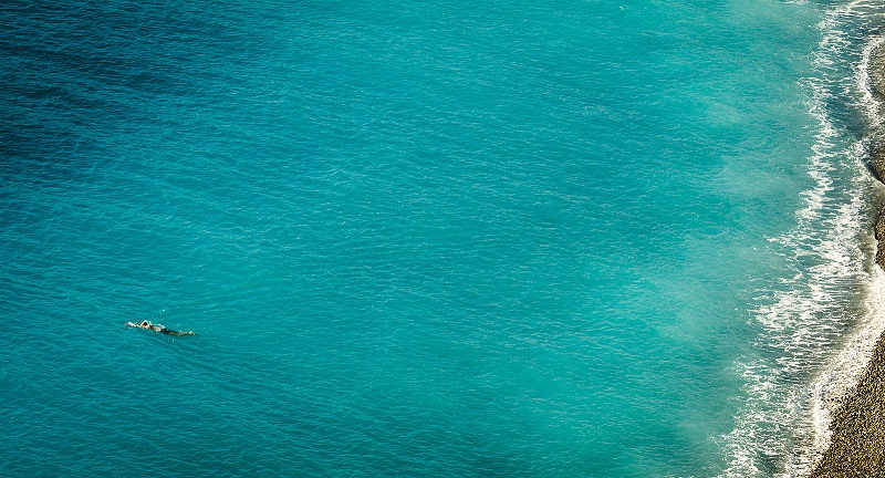 A woman swimming in a dark green-blue sea.