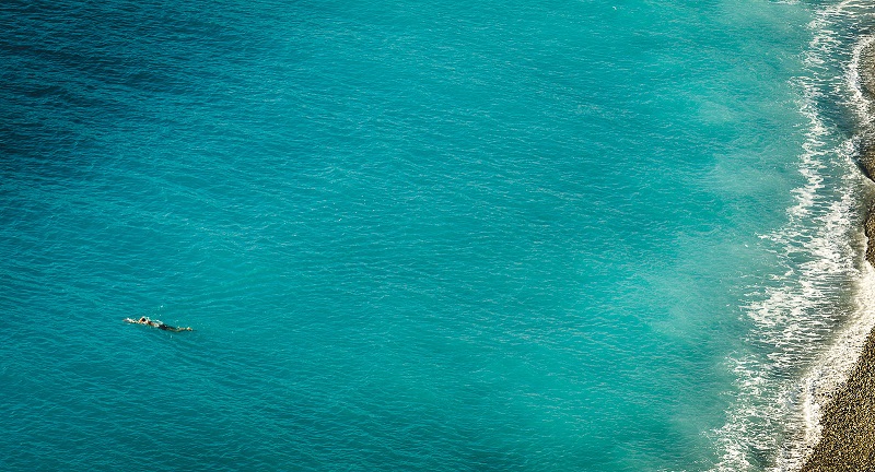 A woman swimming in a dark green-blue sea.