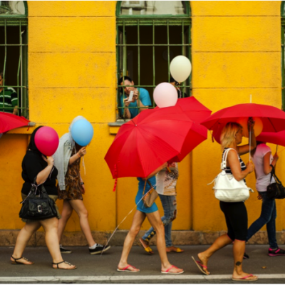 A group of women walking holding red umbrellas that cover their faces.