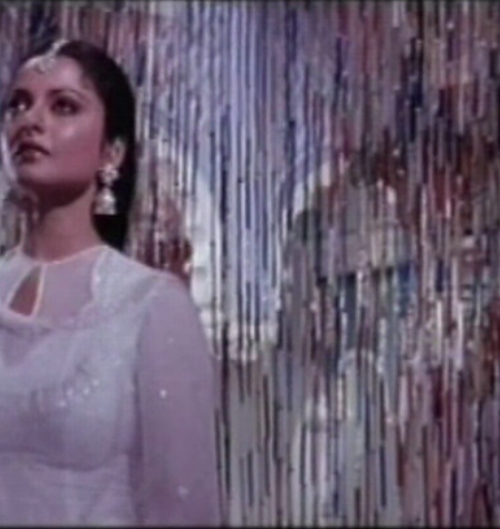 Still from a Bollywood song. A woman in white dress.