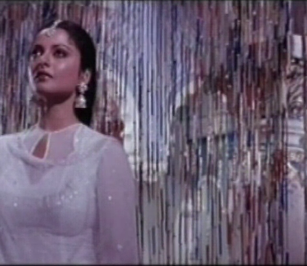 Still from a Bollywood song. A woman in white dress.