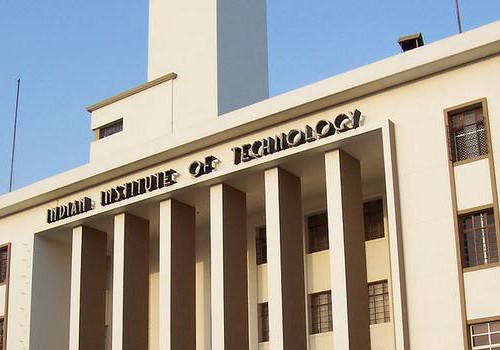 Photo of a front of a light yellow-painted college building. At the top of the building are the words, "Indian Institute of Technology".
