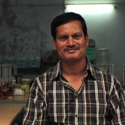 Arunachalam Muruganantham smiling at the camera. He has a moustache, and wearing a checked black and white shirt.