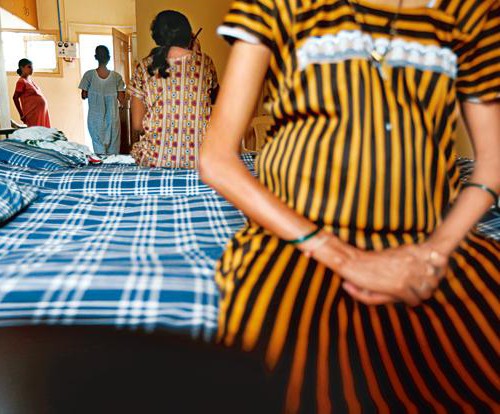 A malnourished pregnant woman sitting on a hospital bed. She is wearing a striped yellow and black gown. Screen reader support enabled. A malnourished pregnant woman sitting on a hospital bed. She is wearing a striped yellow and black gown.