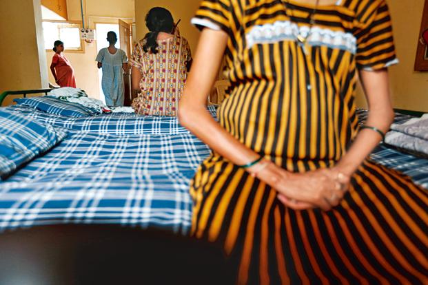 A malnourished pregnant woman sitting on a hospital bed. She is wearing a striped yellow and black gown. Screen reader support enabled. A malnourished pregnant woman sitting on a hospital bed. She is wearing a striped yellow and black gown.