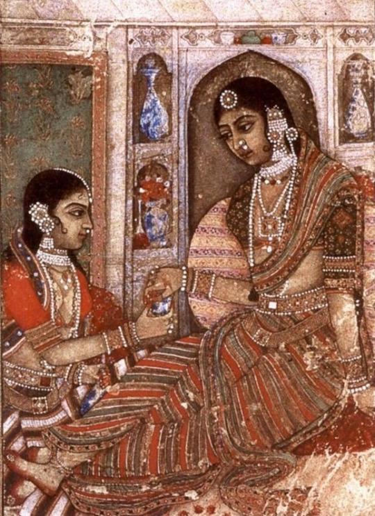 Artwork showing two women sitting, both wearing saree and heavy jewellery. Screen reader support enabled. Artwork showing two women sitting, both wearing saree and heavy jewellery.