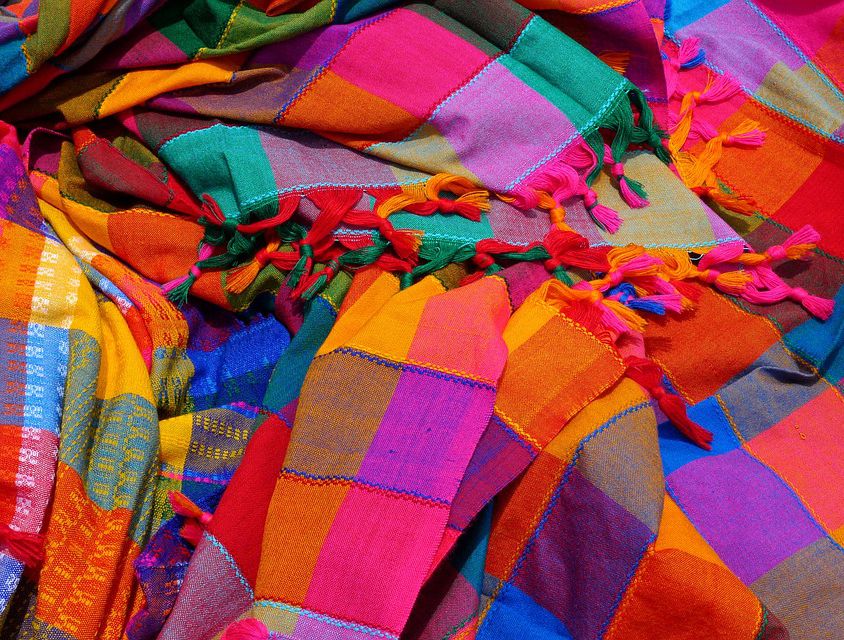 Bright, goddy-coloured shawls lying in a messy, scattered way. Screen reader support enabled. Bright, goddy-coloured shawls lying in a messy, scattered way.
