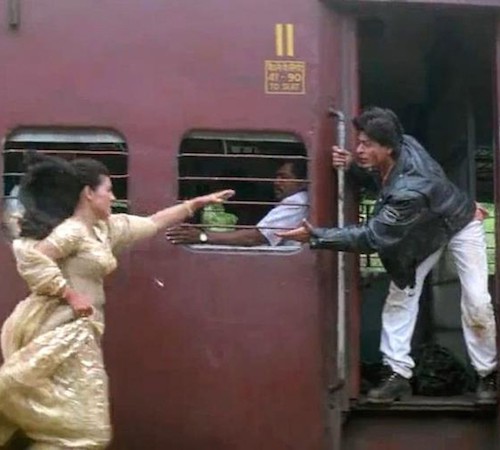 Still from DDLJ, Kajol running towards a running train while Shah Rukh Khan extenda a hand from the train