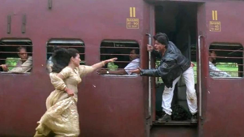 Still from DDLJ, Kajol running towards a running train while Shah Rukh Khan extenda a hand from the train