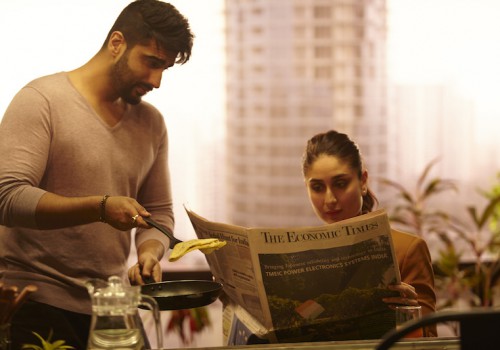 हिंदी फिल्म 'की एंड का' का एक दृश्य है, एक पुरुष और स्त्री, जो फिल्म में पति-पत्नी का किरदार निभा रहे हैं ।खाने की टेबल पर बैठी पत्नी अखबार पढ़ रही है और पति खाना परोस रहा है।