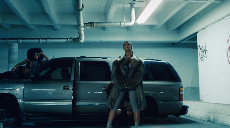 A woman stands infront of a car