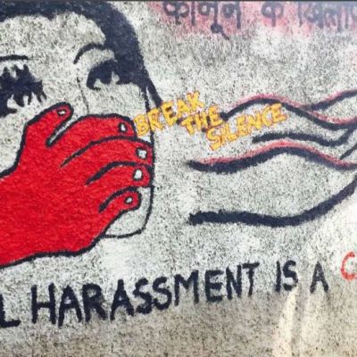 The photo shows a red hand trying to shut the mouth of a woman. There’s a caption on the photo saying sexual harassment is a crime and a yellow caption in between says, break the silence.
