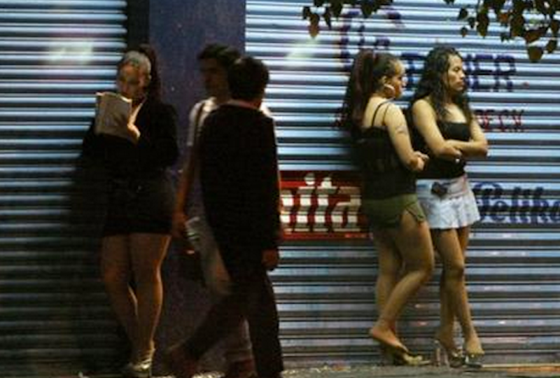 A picture featuring a candid click of a man passing a street which has a number of women standing on the road.