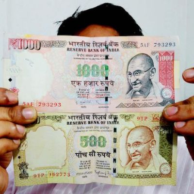 A photo of a man holding the old Rs.1000 and Rs.500 notes,