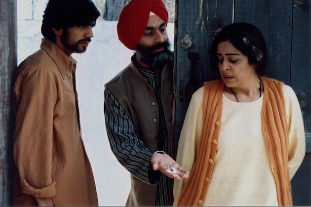 Its a still from the movie, Khamosh Pani,featuring Kirron Kher, standing with her back towards two men, one is a Sikh wearing a red turban offering something to the woman and the other man is looking towards them. Screen reader support enabled. Its a still from the movie, Khamosh Pani,featuring Kirron Kher, standing with her back towards two men, one is a Sikh wearing a red turban offering something to the woman and the other man is looking towards them.