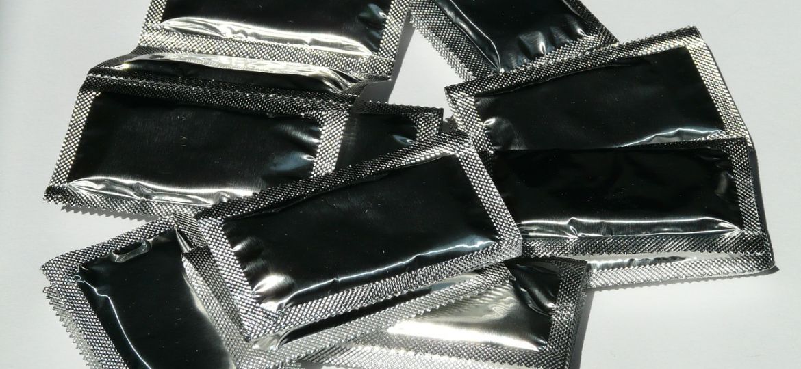 Photo of a strip of small black plastic packets of contraceptives.