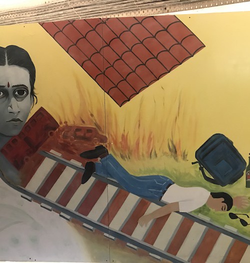 Art work shows a man lying on a railway line to commit suicide. A woman wearing a red bindi and a white saree stares straight ahead in grief.