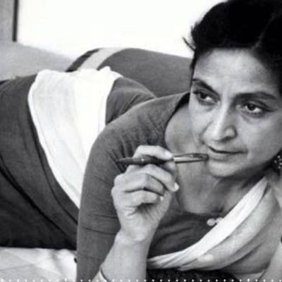 Black-and-white photo of saree-clad writer Amrita Pritam, holding a pen by her cheek thinking something.